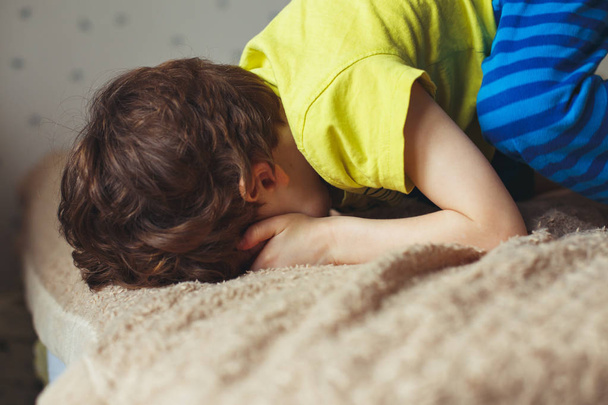 Zmęczony toddler chłopiec leżąc na łóżku twarzą w. Małe dziecko płacze - Zdjęcie, obraz