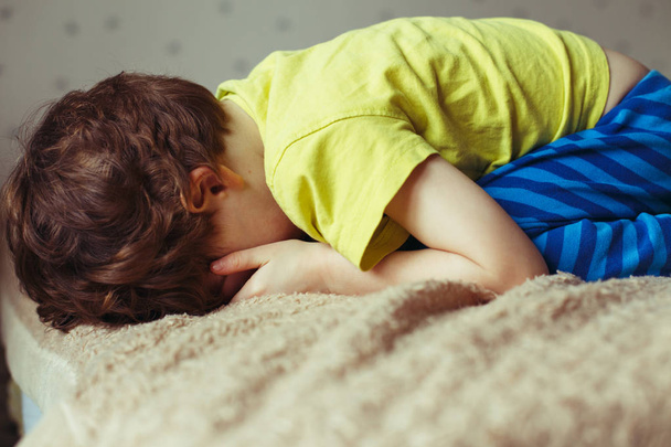 Tired toddler boy lying on the bed with his face down. Crying little kid - Фото, зображення