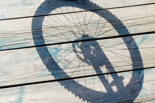 Shadow from a bicycle wheel on a wooden background - Φωτογραφία, εικόνα