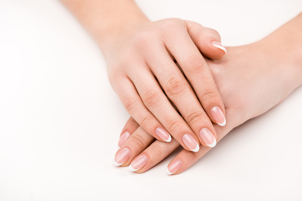 bijgesneden beeld van vrouwelijke handen met natuurlijke manicure, geïsoleerd op wit - Foto, afbeelding