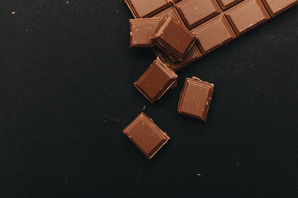 delicious sweet chocolate bar pieces on black background - Photo, Image