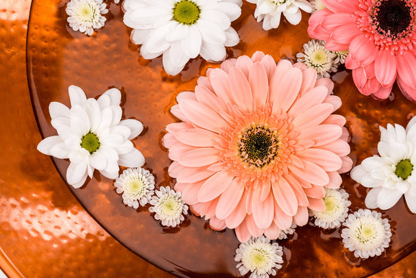 top view of daisies and gerbera flowers in metalic plate for spa procedure - Foto, Imagen