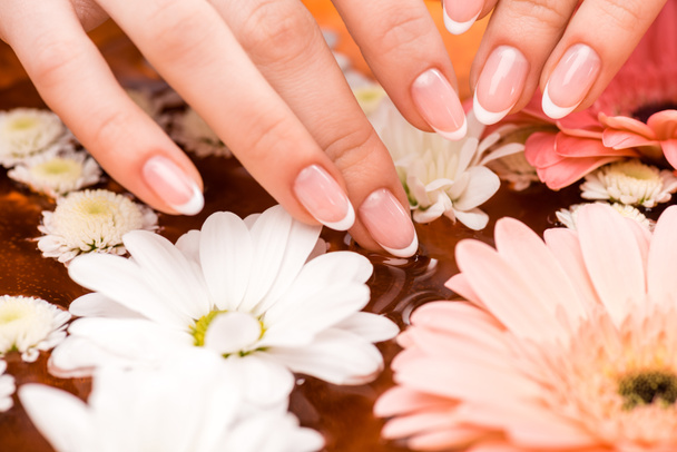cropped view of woman making spa procedure with flowers for nails - Photo, Image