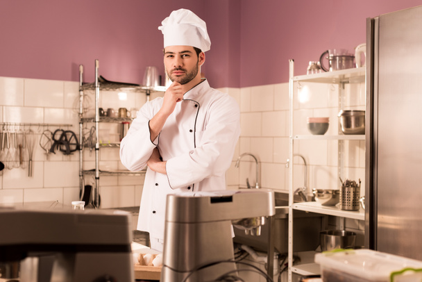 portrait of pensive confectioner standing at counter in restaurant kitchen - Fotografie, Obrázek