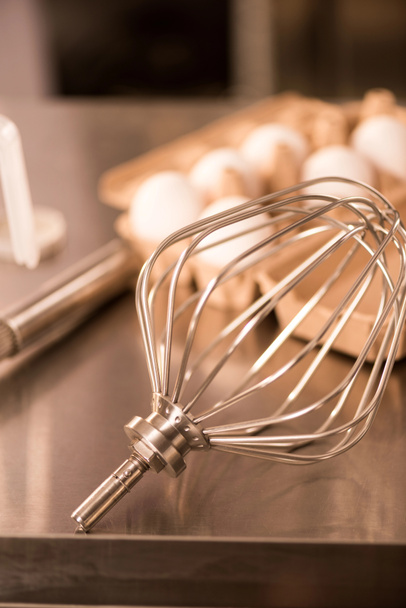 Nahaufnahme von Schneebesen und rohen Eiern zur Herstellung von Sahne auf der Theke im Restaurant - Foto, Bild
