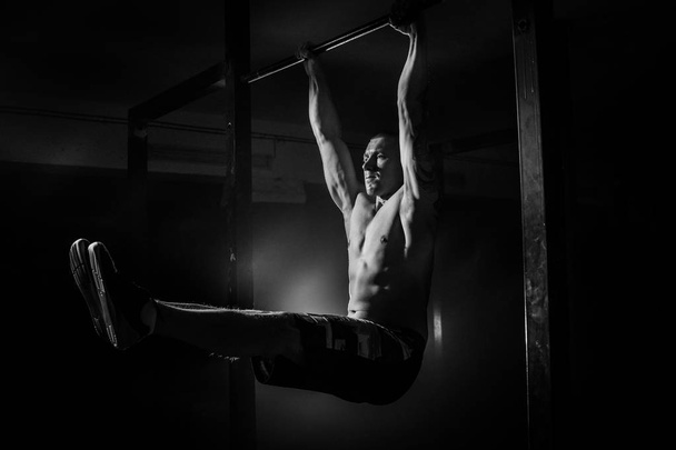 Hombre haciendo ejercicios para los músculos de las manos en el travesaño. Blanco y negro
 - Foto, imagen