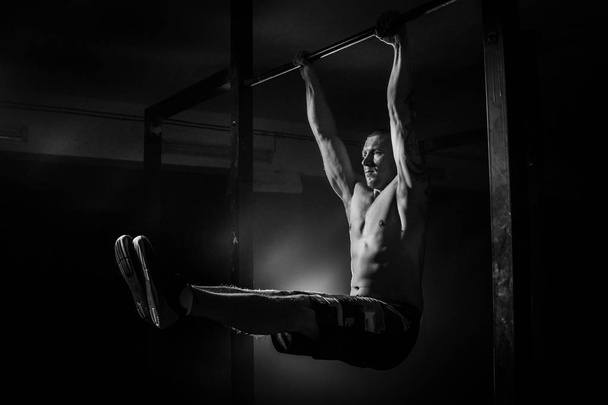 Hombre haciendo ejercicios para los músculos de las manos en el travesaño. Blanco y negro
 - Foto, imagen