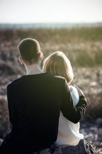 Un couple aimant est assis dans les bras sur le lac
. - Photo, image