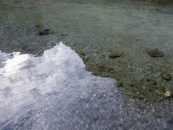 Vue aérienne de l'eau transparente d'un lac de montagne, de cailloux et de rochers sur le lit de la rivière
 - Photo, image