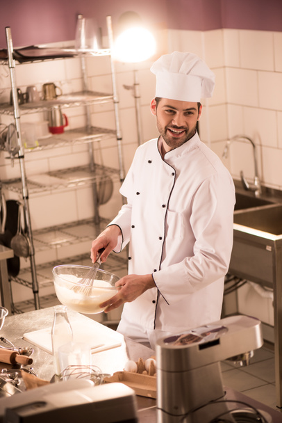 smiling confectioner in chef hat making dough in restaurant kitchen - 写真・画像