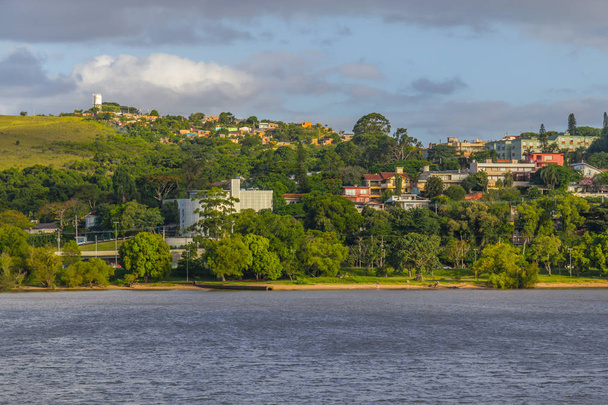 Playa del lago Guaiba con edificios y árboles
 - Foto, Imagen