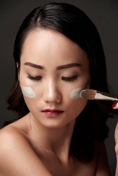 Gyönyörű ázsiai nő szintetikus ecsettel Arc maszk - Fotó, kép
