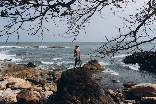 Woman wearing glasses standing on cliff on marine background - Zdjęcie, obraz