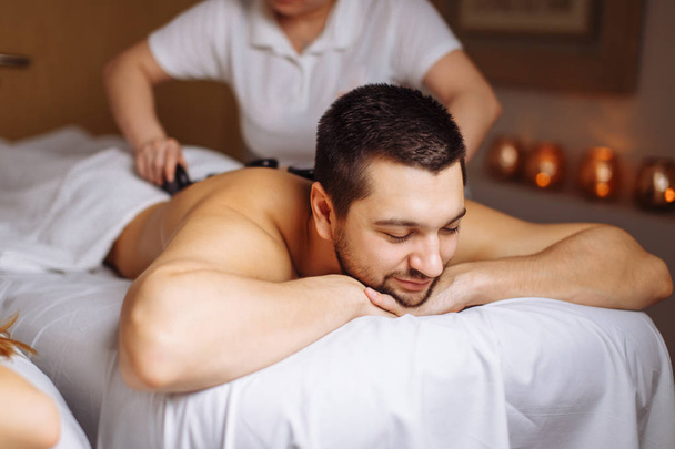 man having stone massage in spa salon. Healthy lifestyle concept - Foto, immagini