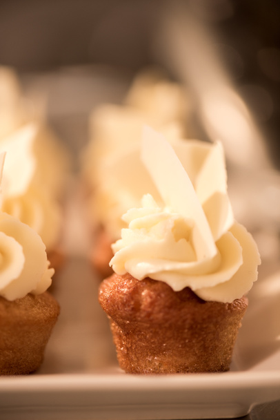 close up view of sweet cupcakes on plate on counter in restaurant kitchen - Photo, Image