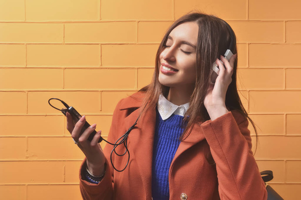 Woman standing and listening to music on headphones - Foto, afbeelding