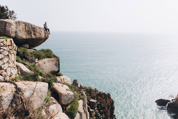 View of man relaxing on edge of cliff and enjoying marine view - Foto, Bild