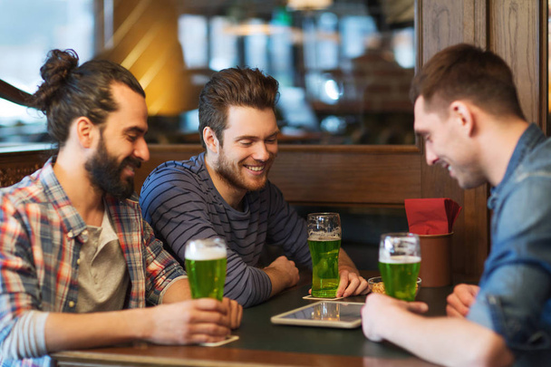friends with tablet pc and green beer at pub - 写真・画像