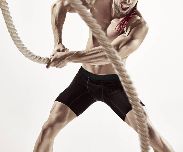 Attractive muscular man working out with heavy ropes. - Foto, imagen