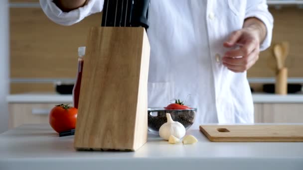 Chef in modern kitchen sharpens knife - Кадри, відео