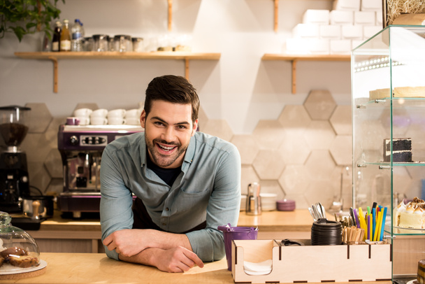 retrato de barista alegre apoyado en el mostrador en la cafetería
  - Foto, imagen