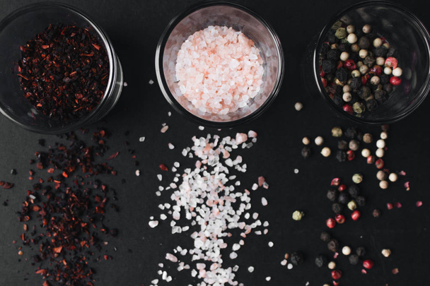 copos com sabor a sal, pimenta variada e especiarias vermelhas no fundo preto
 - Foto, Imagem