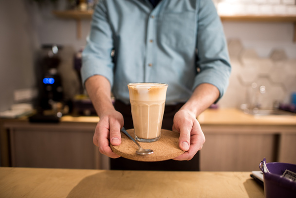 przycięte strzał barista z szklanką kawy lód na tacę w ręce w kawiarni - Zdjęcie, obraz