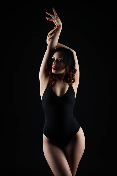 Beautiful sexy woman in bodysuit posing on black background, low key studio shot - Фото, изображение