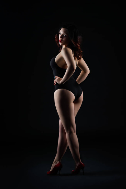Beautiful sexy woman in bodysuit posing on black background, low key studio shot - Fotó, kép