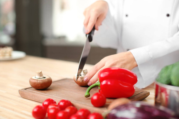 Female chef cutting vegetables in kitchen, closeup - Foto, afbeelding