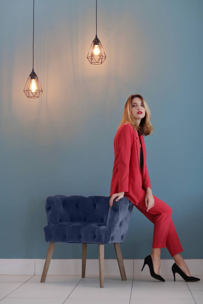 Beautiful young stylish woman and armchair near color wall - Foto, Bild