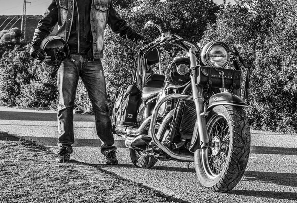Motociclista em pé por uma motocicleta clássica em preto e branco
 - Foto, Imagem