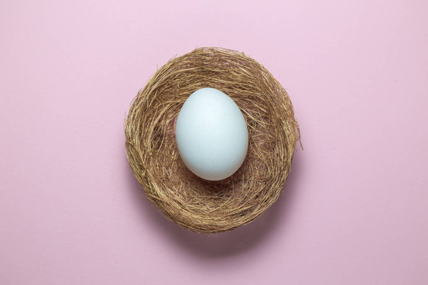 Flat lay of an egg in nest on plain pink background - Photo, Image
