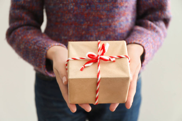 Woman holding parcel gift box on light background - Foto, Imagen