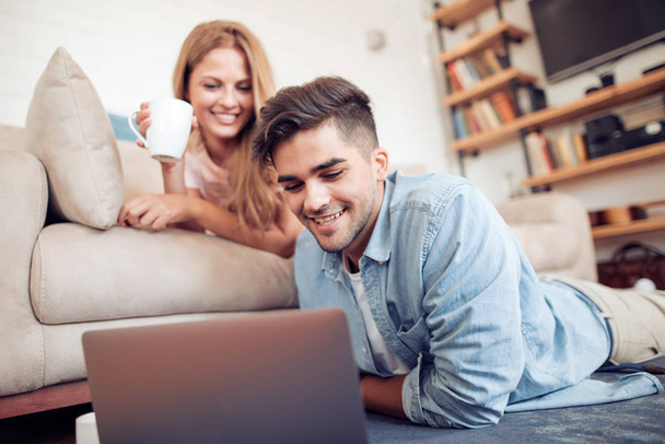 Casal assistindo a um filme no laptop em sua sala de vida.Amor, tecnologia, internet e conceito de pessoas
. - Foto, Imagem