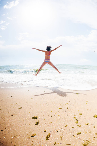 Una ragazza sta saltando sulla spiaggia
. - Foto, immagini