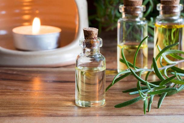 A bottle of rosemary essential oil with rosemary twigs and an ar - Photo, Image