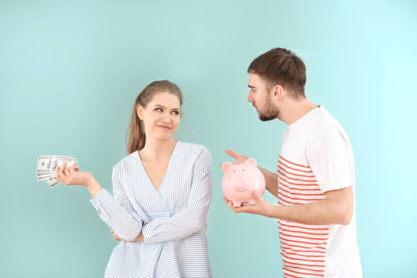 Šťastná žena držící peníze a rozhořčený muž s prasátko na barvu pozadí. Problémy ve vztahu - Fotografie, Obrázek