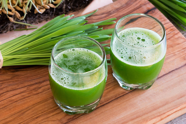 Two glasses of barley grass juice with freshly grown barley gras - Fotó, kép