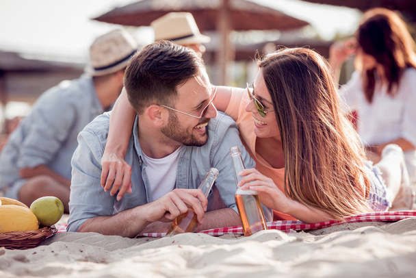 Πορτρέτο του ευτυχισμένο ζευγάρι μαζί στην παραλία, έχουν τη διασκέδαση και ποτό μπύρα. - Φωτογραφία, εικόνα