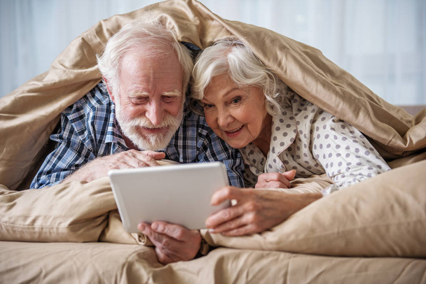 Glad pensioners surfing the internet in bedroom - Valokuva, kuva
