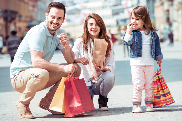 Famille heureuse avec petite fille et sacs à provisions dans la ville.Concept de vente, de consumérisme et de personnes
. - Photo, image