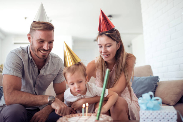 Γιορτή, οικογένεια, διακοπές και γενέθλια έννοια - ευτυχισμένη οικογένεια με κέικ στο σπίτι - Φωτογραφία, εικόνα