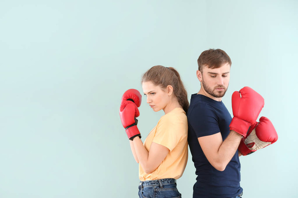 Couple fighting in boxing gloves on color background. Problems in relationship - 写真・画像
