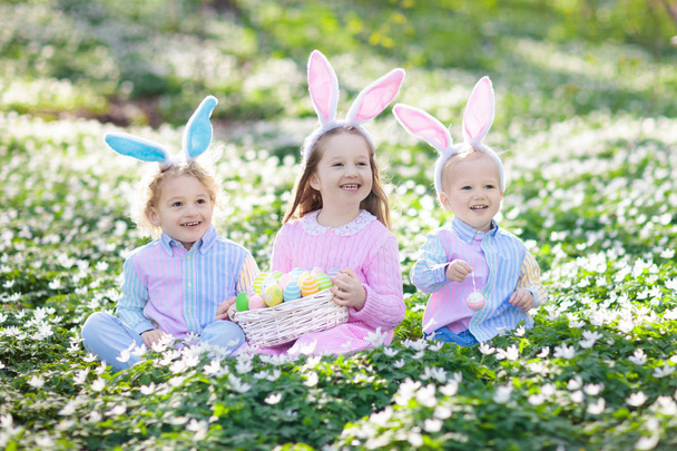 Enfants avec des oreilles de lapin sur la chasse aux œufs de Pâques
. - Photo, image
