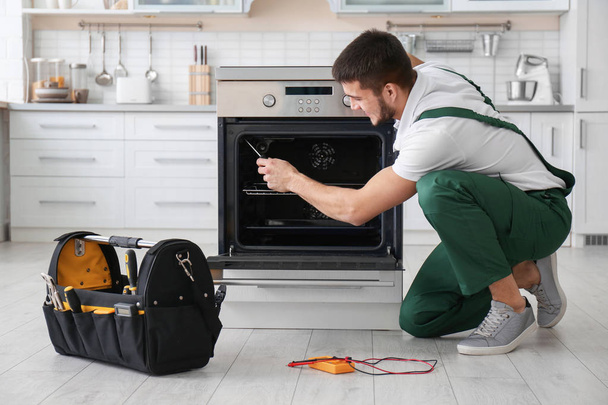Young man repairing oven in kitchen - Photo, Image