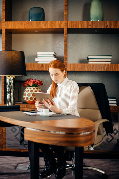 Businesswoman wearing glasses using digital tablet in office - Фото, изображение