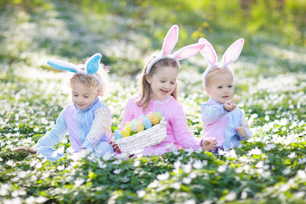 Niños con orejas de conejo en la búsqueda de huevos de Pascua
. - Foto, imagen