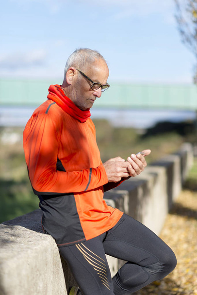 Senior runner man watching his smartphone after jogging - Valokuva, kuva