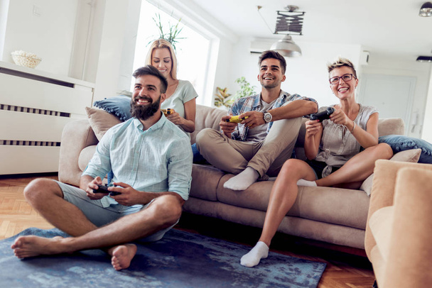 Groep volwassen vrienden zitten in modern appartement en het spelen van videospellen. - Foto, afbeelding